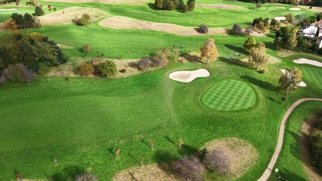 An aerial view showcases a sprawling golf course with lush fairways, sand bunkers, and scenic landscaping