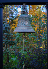 Obraz premium An old bell hanging on a wooden frame in the courtyard of a church on a summer day