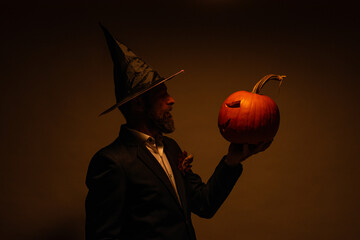 model with Halloween pumpkin. Portrait of Man in Halloween hat with pumpkin. Trick or treat. Scary hipster with beard in Halloween hat. Man with witch