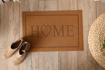 Door mat with shoes on floor in hallway, top view