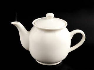 A white teapot elegantly positioned against a contrasting black background, highlighting its shape and design