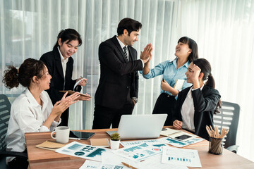 Group of happy businesspeople in high five gesture and successful efficient teamwork. Diverse race office worker celebrate after made progress on marketing planning in corporate office. Habiliment