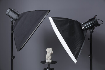 Modern photo studio with stool, figurine and professional lightening equipment