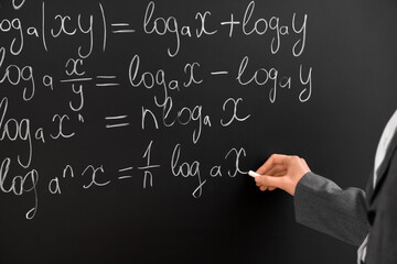 Female math teacher writing on blackboard in classroom