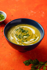 Creamy Roasted Pumpkin Soup with truffle, green onion and coriander served in bowl isolated on orange background closeup side view of hot drink
