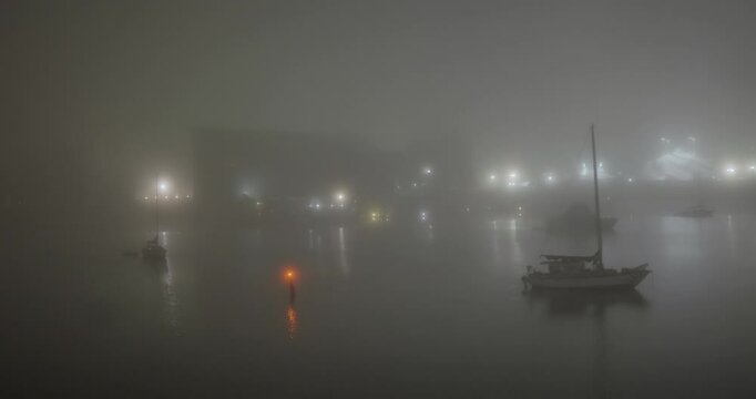 boats in the harbor during a foggy winter night