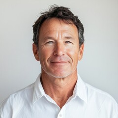 Confident middle-aged man smiling in white shirt against neutral background