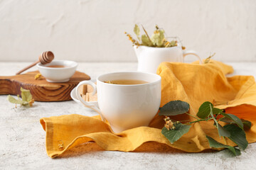 Cup of tasty linden tea with leaves on white grunge background