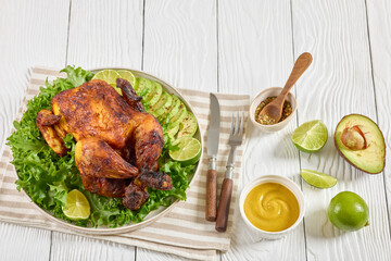 whole roasted chicken with avocado, lime on plate