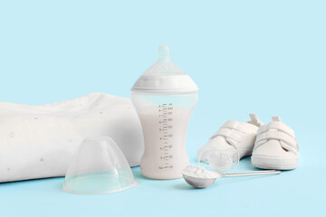 Bottle with baby milk formula, pacifier, booties and pillow on color background