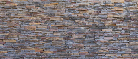 Natural stone wall background texture in earthy and grayish tones, with irregularly stacked blocks
