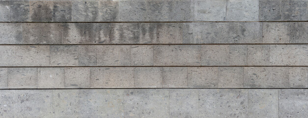 Panoramic wall background with smooth and uniform textured gray stone blocks