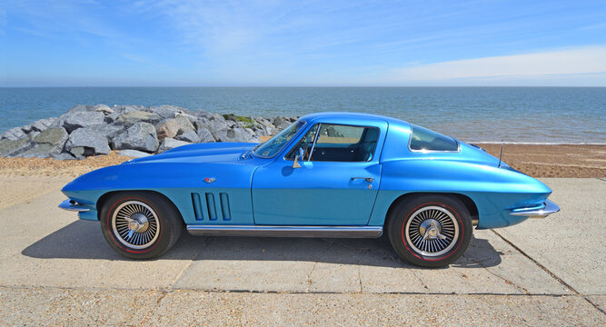 Classic  Chevrolet Corvette C2 parked on seafront promenade  beach and sea in background