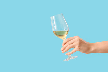Female hand holding glass of wine on blue background