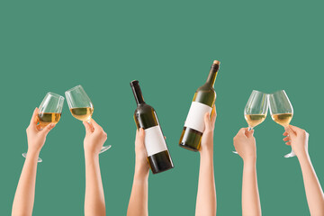 Female hands holding bottles and glasses of wine on green background