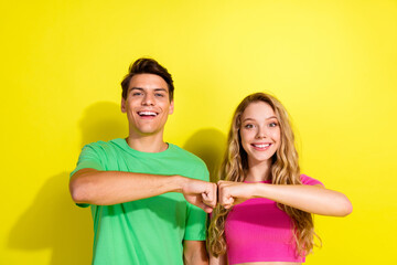Obraz premium Portrait of two nice young partners toothy smile fist bumps wear t-shirt isolated on vibrant yellow color background