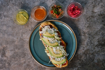 Huarache comida mexicana con salsa verde y roja, pico de gallo y cebolla morada