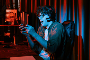 Fototapeta premium Stressful young gaming streamer team playing with Esport online on smartphone fighting harder game level with surprise face and shame for winning at neon light room. Practising strategy plan. Gusher.