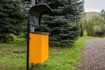 Garbage bin in green spruce garden, ecological concept