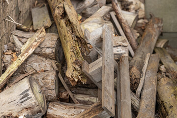 Pile of old and weathered wooden logs and planks stacked outdoors in a rustic environment. Concept of natural decay, recycling materials, and wood textures in nature