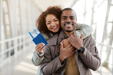 Vacation Travel. Lovely Black Couple Embracing Holding Passports Posing With Suitcase Smiling To Camera Outdoors Airport Terminal. Shot Of Tourists Waiting For Flight. Transportation And Tourism. High