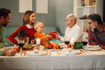 Happy family having christmas dinner together at home giving presents