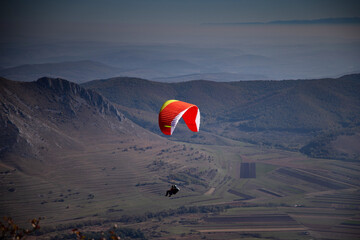 red paraglider flying over mountain