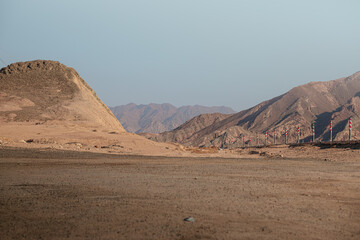mountain range landscape. The mountains are characterized by sharp rocky outcroppings and steep slopes covered with rocks and little vegetation. The colors of the mountains range from dark brown to li