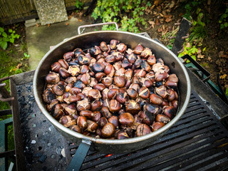 Popular autumn delicacy, baked chestnuts on the hot charcoal in the pan