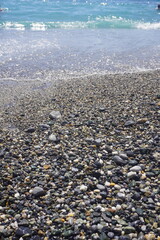 Colorful Assortment of Natural Beach Pebbles and Stones: Ocean-Worn Gems and Minerals on a beach with sea waves 