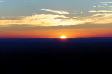 Obraz premium Ein Sonnenuntergang am Horizont mit Wolkenspiel und Abendrot