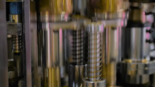 Close up: pneumatic machinery components in motion. Moving parts of paper cup making machine: pistons, cylinders. Abstract, industry, manufacturing, production process and automated technology concept