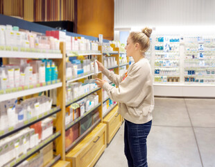 Woman buying make up at cosmetics section in store. choosing cosmetics, perfumes, creams and shampoos, Using tester.