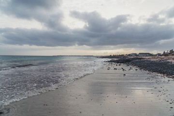 Obraz premium Seascape with ocean and beach in the foreground on a moody cloudy day