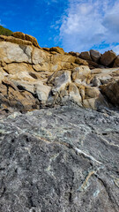Granite and stone formations of light yellow and black colors on one of the islands of the Mediterranean.