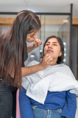 Beautician performing threading hair removal on customer's face