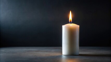 Solitary white candle with small flame on black background