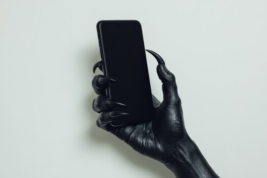 A black hand with claws gripping a sleek smartphone, set against a clean white studio background, with the simplicity of the backdrop enhancing the boldness of the hand.