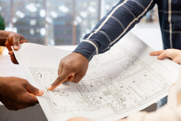 Business people examining blueprints and sketches with realtor during high class office space tour,...