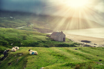 Sandy beach, mountain and rising sun in dramatic blue cloudy sky. Keem bay, Ireland. Famous tourist...