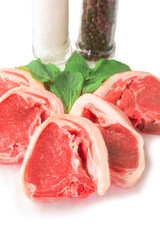 Fresh uncooked lamb loin chops and mint leaf on white background. High quality meat product cut by butcher in perfect size for cooking. Food supply chain and agriculture industry.