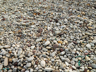 A pile of rocks with a few brown ones. The rocks are scattered and there is a green rope in the middle