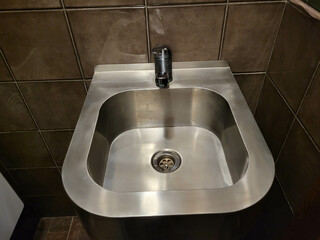 There is a metal sink and a faucet in the bathroom.