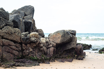 View of dark sea rocks against the ocean and cloudy sky. Preserved nature.