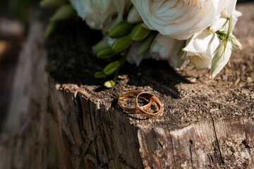 Elegant Wedding Rings on Rustic Wooden Surface with White Roses Bouquet