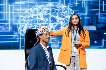 Smiling neuroscientists talking at AI convention, sharing neural implants industry insights to audience. Upbeat tech startup employees at tech event presenting latest AI EEG headsets