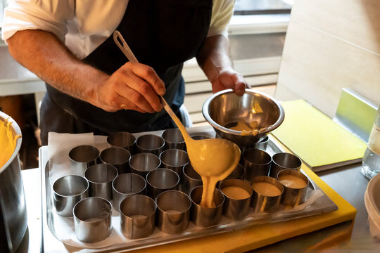 Chef precisely pouring batter into molds in a professional kitchen