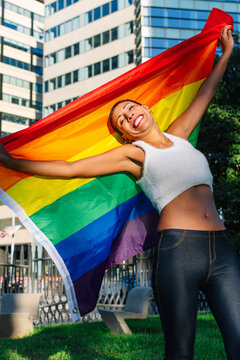 Joyful woman with a pride flag in an urban setting
