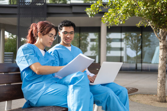 Nurse students studying with laptop and paperwork outdoors
