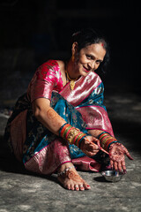 A traditional Indian woman is dressed in a beautiful saree is ready to color her foot with aalta.